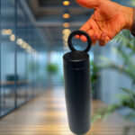 Hand holding black travel mug in office.