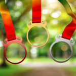 Glass medals with metallic frame on ribbon in sunlight